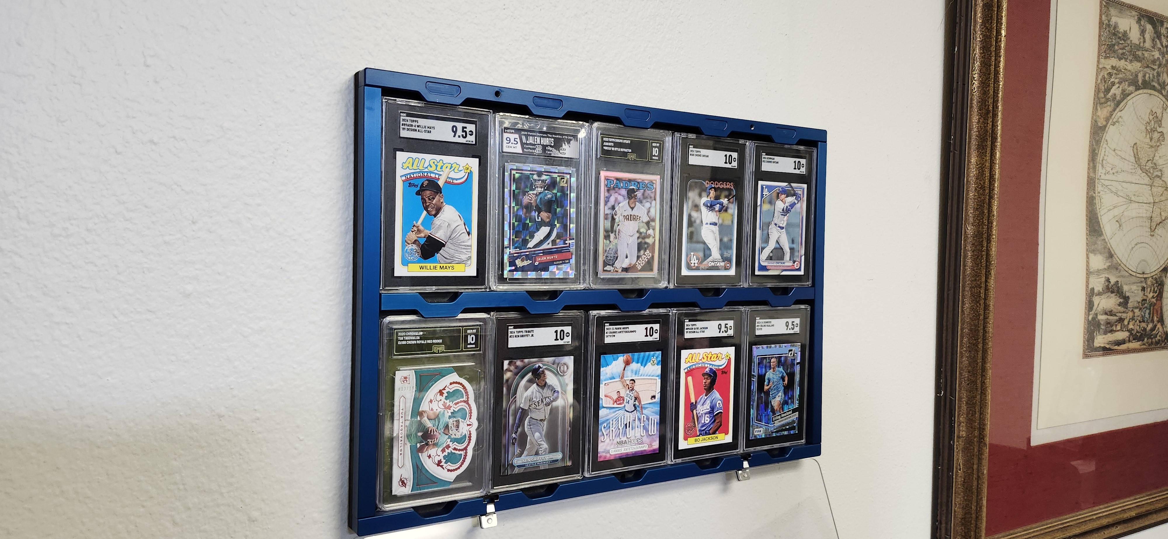 Blue anodized Standard Display wall-mounted with 10 graded sports cards including Willie Mays, Jalen Hurts, Ohtani, and Bo Jackson