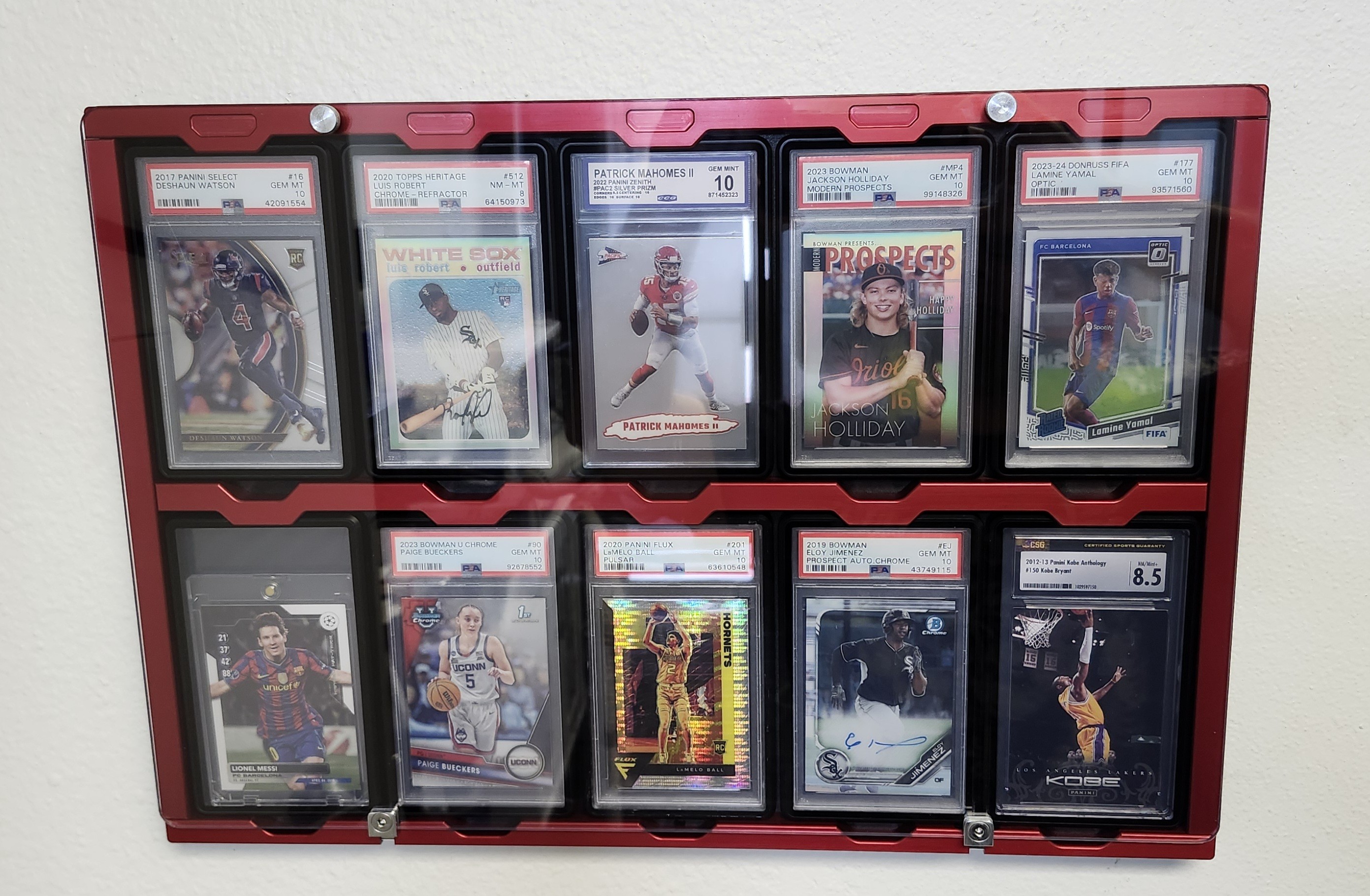 Red anodized Protected Display wall-mounted with 10 PSA graded sports cards including Watson, Robert, Mahomes, Holliday, Yamal, Messi, Bueckers, Ball, Jimenez, and Kobe